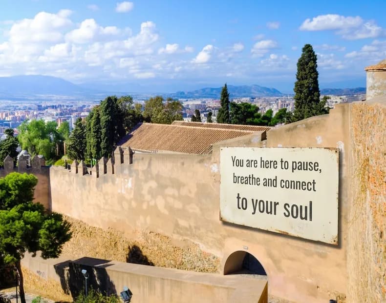 A sign at El Castillo de Gibralfaro reading "You are here to pause, breathe and connect to your soul."