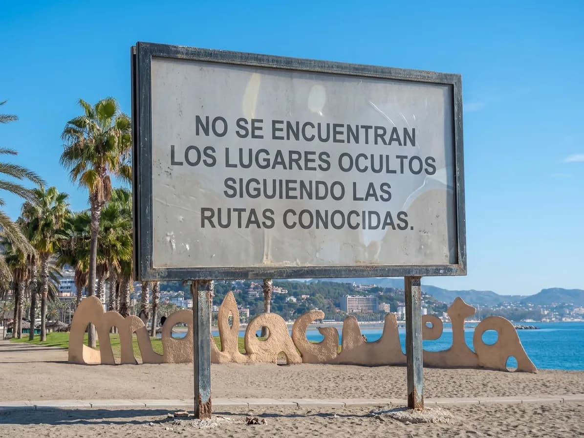 A sign at La Malagueta reading "No se encuentran los lugares ocultos siguiendo las rutas conocidas."