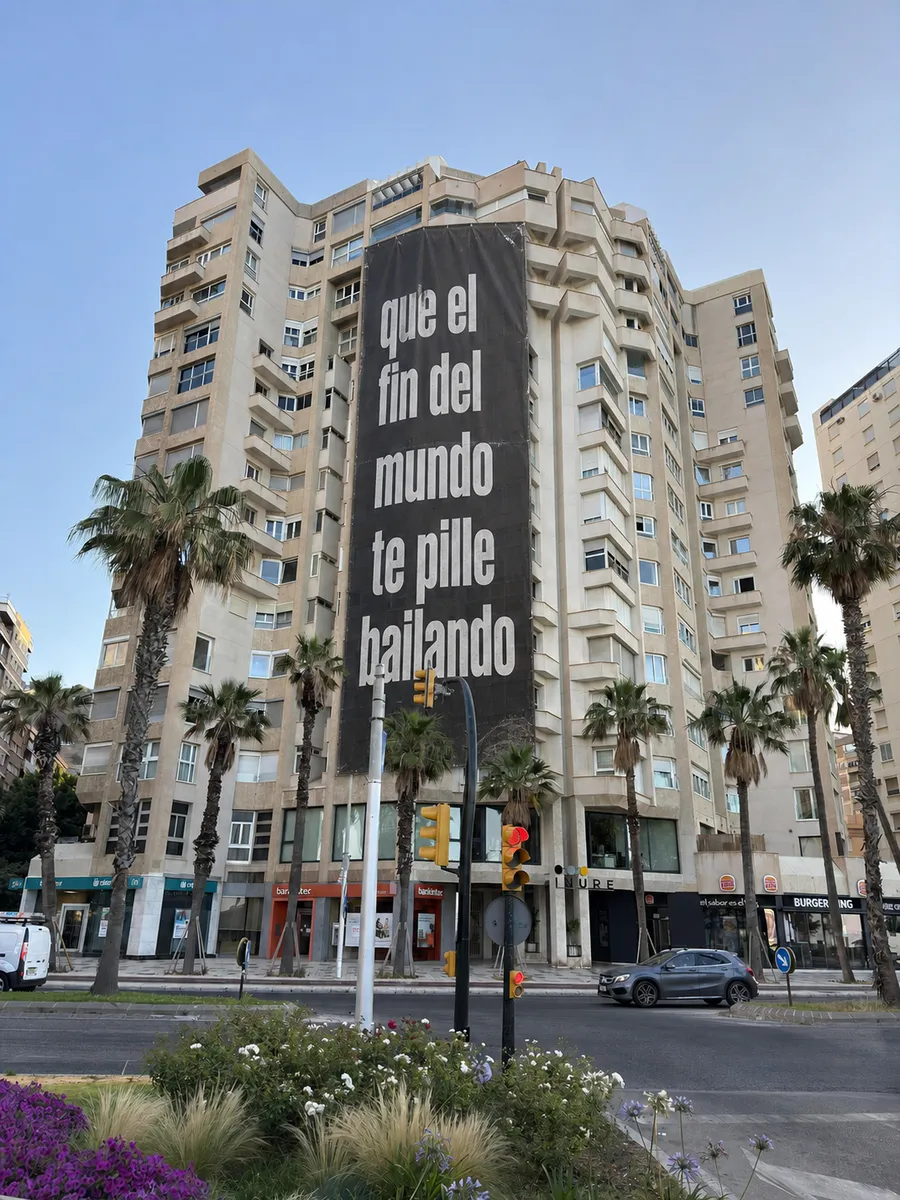 Un cartel gigante en un edificio de Málaga: "que el fin del mundo te pille bailando".